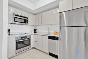 a white kitchen with a refrigerator and a microwave at Modern Condo - Amazing Pool - Gym - Balcony in Hallandale Beach