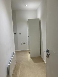 an empty hallway with a white refrigerator in a room at cosy and prime location in Sheffield