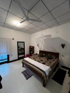 1 dormitorio con 1 cama y ventilador de techo en Little Villa Guest House, en Ahangama