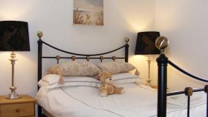 a teddy bear sitting on a bed with two lamps at Sunny Corner - Bright, Spacious Apartment with Harbour Views - 102 in Penzance