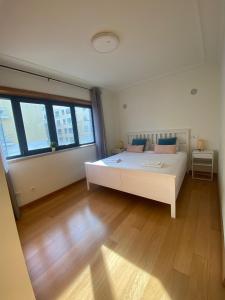 um quarto com uma grande cama branca e pisos em madeira em Bom dia Parque Nações LisboaZ em Lisboa