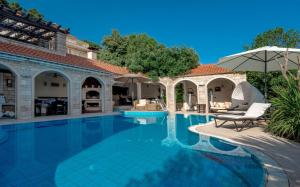 a swimming pool with two chairs and an umbrella at Luxury villa Brac Belle Vue with heated pool in Selca