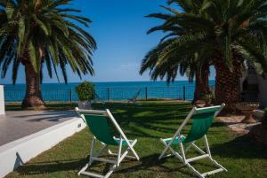 dos sillas sentadas en la hierba cerca del océano en Villa Lucia, en Mattinata