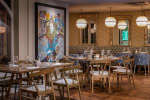 a restaurant with tables and chairs and a painting on the wall at Harbour Hotel & Spa Richmond in Richmond upon Thames