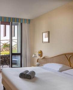 a bedroom with a bed with two towels on it at UNAHOTELS Capotaormina in Taormina