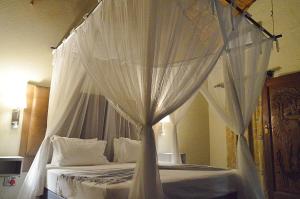 ein weißes Himmelbett mit weißer Bettwäsche und Kissen in der Unterkunft Pan African Lodge & Safari in Marloth Park