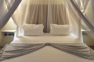ein Himmelbett mit weißer Bettwäsche und Kissen in der Unterkunft Pan African Lodge & Safari in Marloth Park