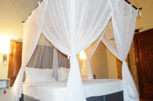 ein Himmelbett mit weißen Vorhängen im Schlafzimmer in der Unterkunft Pan African Lodge & Safari in Marloth Park