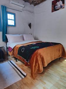 a bedroom with a bed with a blanket on it at Maison d'hôtes Retour Au Calme in Tinerhir