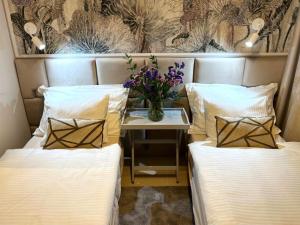 dwa łóżka ze stołem z wazonem kwiatów w obiekcie Apartamento Amarillo Oceanview w mieście Playa Fañabe