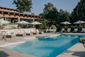una piscina con tumbonas y sombrillas en La Villa Hotel, en Mombaruzzo
