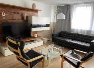 a living room with a black couch and a table at H&H Apartment im Herzen der Stadt Nr 17-Karl mit Küche, Wohnzimmer und Esstisch in Greifswald