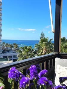 balkon z fioletowymi kwiatami i widokiem na ocean w obiekcie Apartamento Amarillo Oceanview w mieście Playa Fañabe