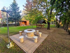 a picnic table and benches in a park with a tent at Lovas Vendégház in Tiszafüred