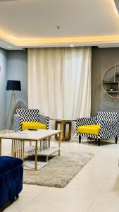 a living room with yellow and white chairs and a table at One Bed Appartment in GoldCrest Mall and residency DHA Lahore in Lahore