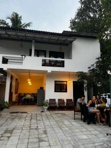 un grupo de personas sentadas en mesas fuera de una casa en Little Villa Guest House, en Ahangama