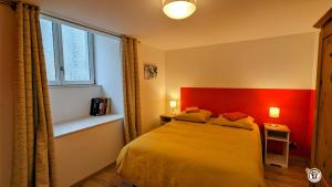 ein Schlafzimmer mit einem Bett mit rotem Kopfteil und einem Fenster in der Unterkunft Marionnette in Baulme-la-Roche