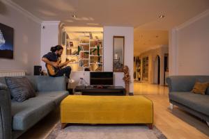 a man is playing a guitar in a living room at Fresh room with a balcony in a digital nomad house in Istanbul
