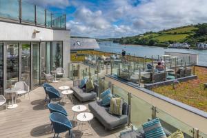 taras z krzesłami i stołami oraz widokiem na wodę w obiekcie Harbour Hotel & Spa Salcombe w mieście Salcombe