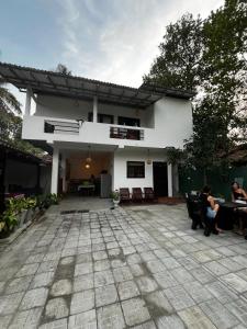 una casa blanca con gente sentada en un patio en Little Villa Guest House en Ahangama