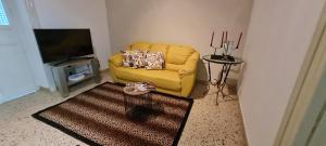ein Wohnzimmer mit einem gelben Sofa und einem TV in der Unterkunft CASA VACANZE PIAZZA GRAZIA in Caltanissetta