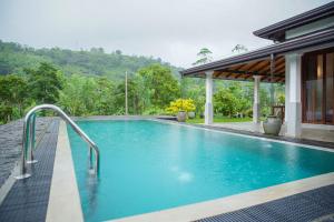 a swimming pool in front of a house at Plantation Villa in Baddegama