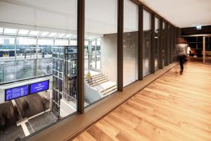 a person walking down a hallway in a building with windows at IntercityHotel Paderborn in Paderborn