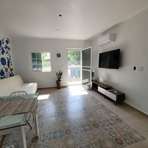 Una sala de estar con un sofá y un televisor de pantalla plana. en The Villa Bokobá, en Isla Mujeres