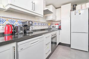a white kitchen with white cabinets and appliances at Casa Venus in Salobreña