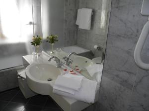 a white bathroom with a sink and a tub at Hotel Cappelli in Montecatini Terme