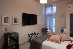 - une chambre avec un lit et une télévision murale dans l'établissement Palazzo Marzionna, à Polignano a Mare