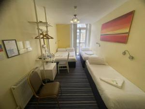 Cette chambre comprend 4 lits, une table et des chaises. dans l'établissement Manor Hotel, à Londres