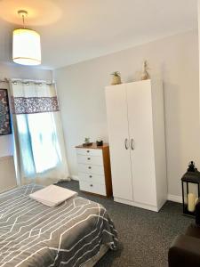 a bedroom with a bed and a dresser and a window at Homestay in Waltham Abbey