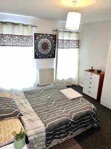 a bedroom with a bed and two windows at Homestay in Waltham Abbey