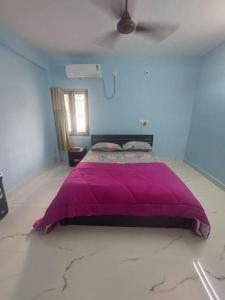 a bedroom with a purple bed in a blue room at The Sweet Home in Chennai