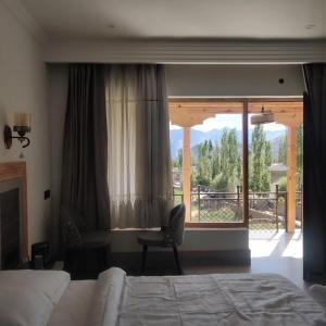 um quarto com uma cama, uma cadeira e uma janela em The Morning Sky hotel em Leh