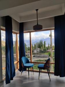 a room with two chairs and a large window at The Morning Sky hotel in Leh