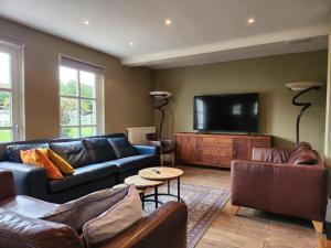 een woonkamer met een bank en een flatscreen-tv bij Landhuis de heibloem in Heythuysen