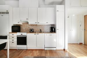 a white kitchen with white cabinets and a sink at Kotimaailma Apartments Kamppi - 2BR for 4 persons in Helsinki