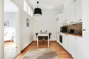 a kitchen with white cabinets and a table with chairs at Kotimaailma Apartments Kamppi - 2BR for 4 persons in Helsinki
