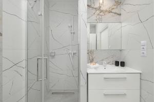 uma casa de banho branca com um chuveiro e um lavatório. em Villa Tarsis Apartment in Kołobrzeg by Rent like home em Kolobrzeg