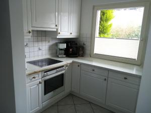 a kitchen with white cabinets and a window at Ferienwohnung Steuerbord in Büsumer Deichhausen