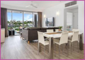 a living room with a couch and a table and chairs at Apartment 1102 | 11th Floor River & Stadium Views in Townsville