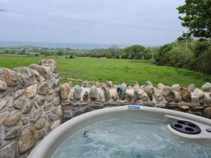 a stone wall with a hot tub in a yard at The Bothy in Caernarfon