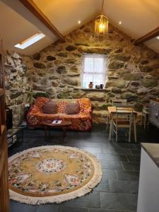 a living room with a couch and a stone wall at The Bothy in Caernarfon