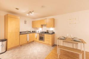 a kitchen with wooden cabinets and a wooden table at Cosy, Modern City Centre Apartment Free Parking in Leicester