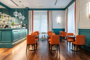 a dining room with orange chairs and tables at Glimpse Hotel in Florence