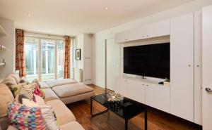 a living room with a couch and a tv at The Clapham Crib - Spacious 4BDR House with Patio in London