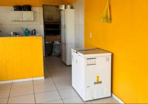 uma cozinha com uma parede laranja e uma máquina de lavar louça branca em Casa na em moitas de Amontada em Praia de Moitas
