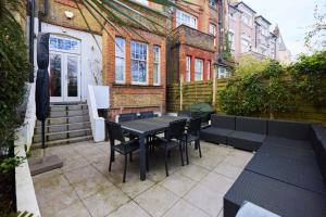 un patio con tavolo, sedie e un edificio di The Clapham Crib - Spacious 4BDR House with Patio a Londra